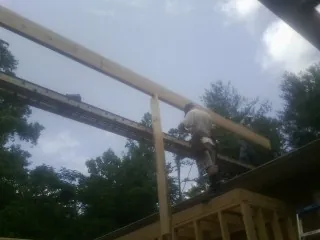 Carpenter setting a ridge beam over a new addition frame — Ice Dam Removal by Roofing Brothers in Mchenry