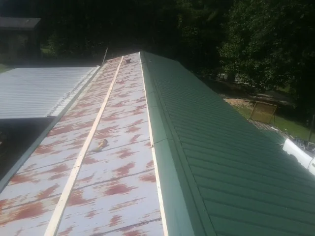 Old rusted panels beside newly installed green metal roofing — Wind Damage Roof Repair by Roofing Brothers in Mchenry