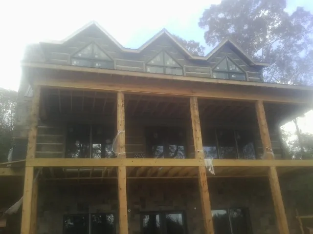 Dormers and porch framing on a large log home under construction — Roof Coating work by our crew in Mchenry