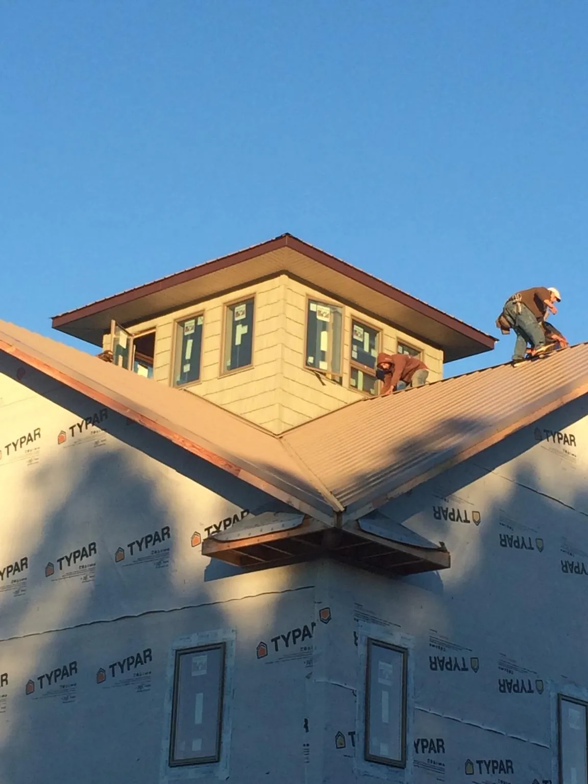 Roofers working around a rooftop cupola on a new metal roof at sunset — Roof Waterproofing in Mchenry by Roofing Brothers